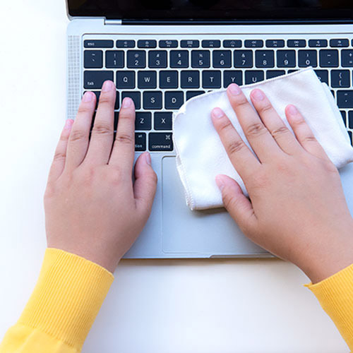 Close-up of woman's hands cleaning digital tablet keyboard with disinfectant wipe
