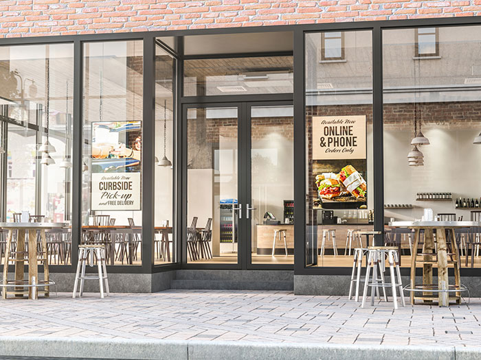 Cafe shown from street. Digital signage directs customers on curbside pickup.