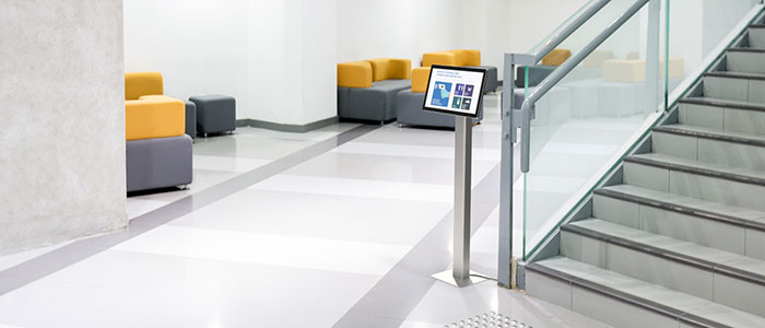 Tablet stand displaying health protocols in a building lobby