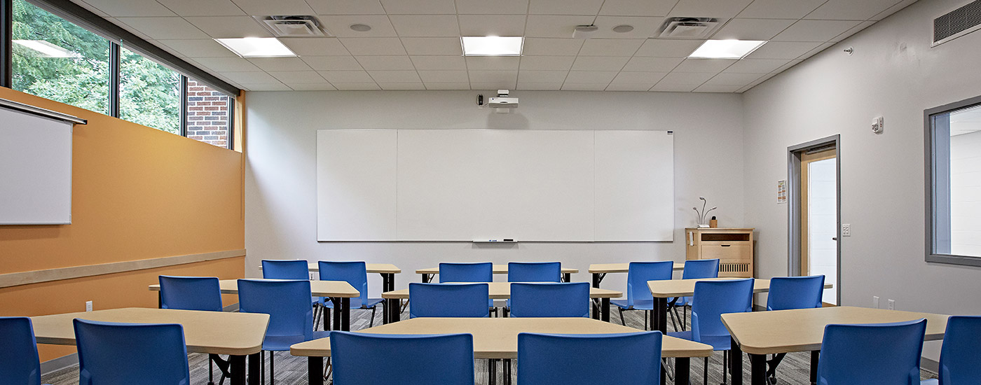 Classroom with IDEA screen at the front and a projection screen on the side. 