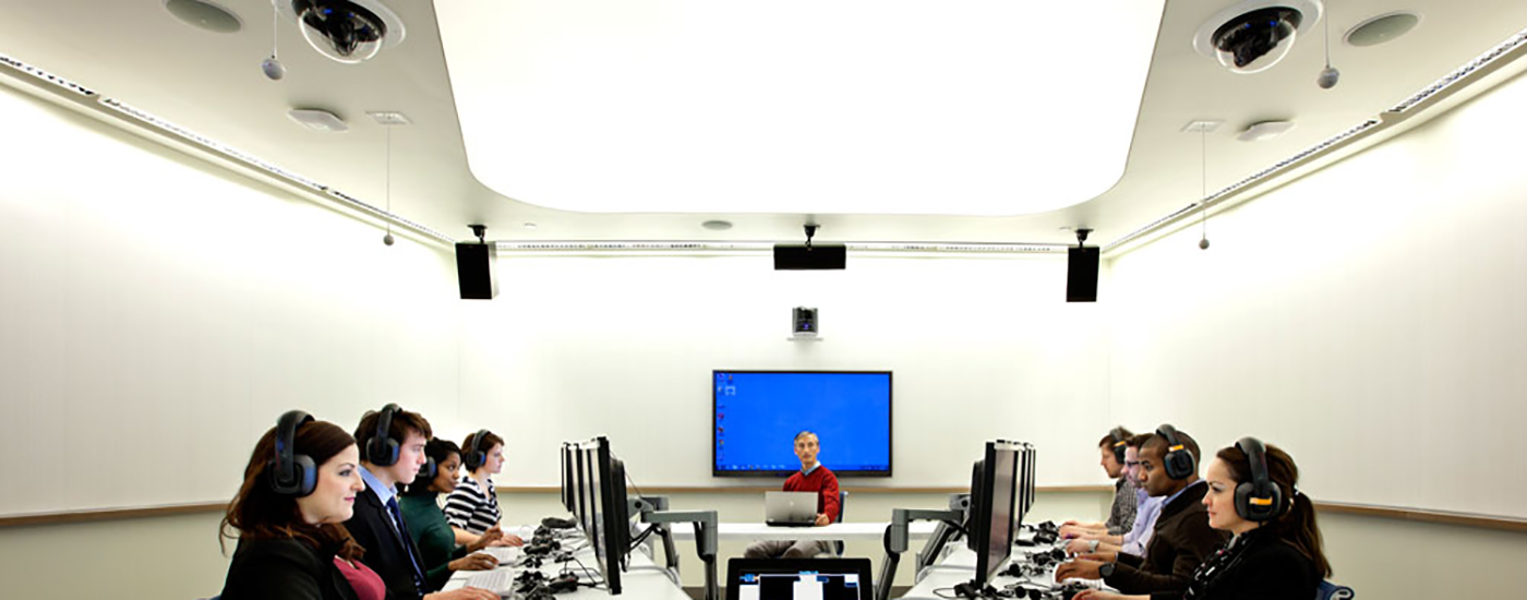 People around a table with computers and headsets