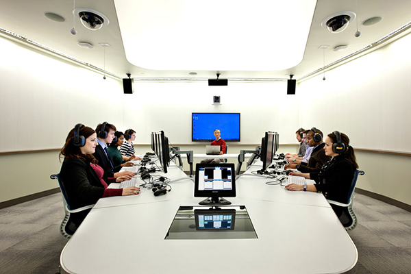 People around a table with computers and headsets