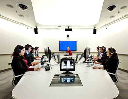 People around a table with computers and headsets