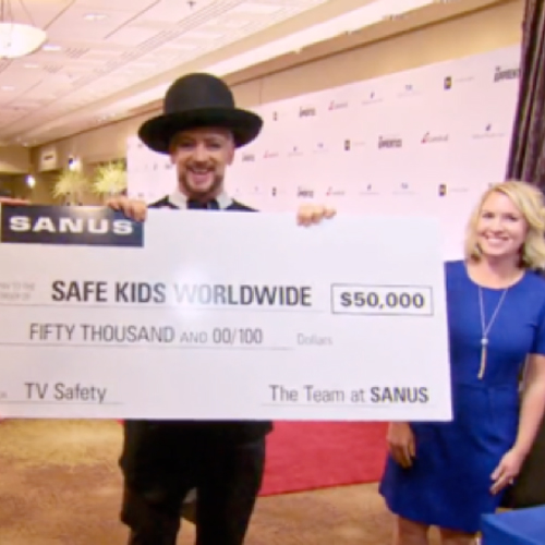 Boy George being presented a $50,000 check from SANUS for the Safe Kids Worldwide charity