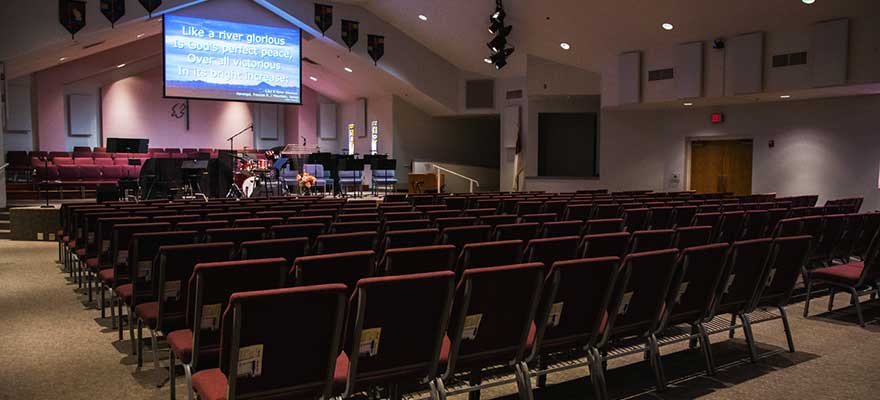 Song lyrics and order of service projected on a screen in a church.